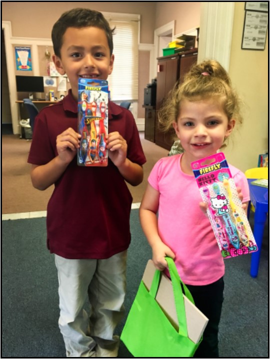 Happy children display their new dental hygiene products (toothbrushes, in this case); gifts from the Orange County Childhood Language Center.